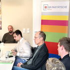 5 Personen sitzen an Tischen eines Seminarraums, im Hintergrund ein Roll-up des Paritätischen Bremen