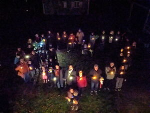Menschen mit Lichtern stehen im Dunkel und bilden ein Lichterherz - Aufnahme aus der Vogelperspektive