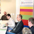 5 Personen sitzen an Tischen eines Seminarraums, im Hintergrund ein Roll-up des Paritätischen Bremen