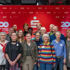 Gruppe von freudigen Menschen vor einer roten Wand der Sparkasse