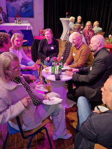 Verschiedene Männer und Frauen sitzen um einen Tisch und sprechen