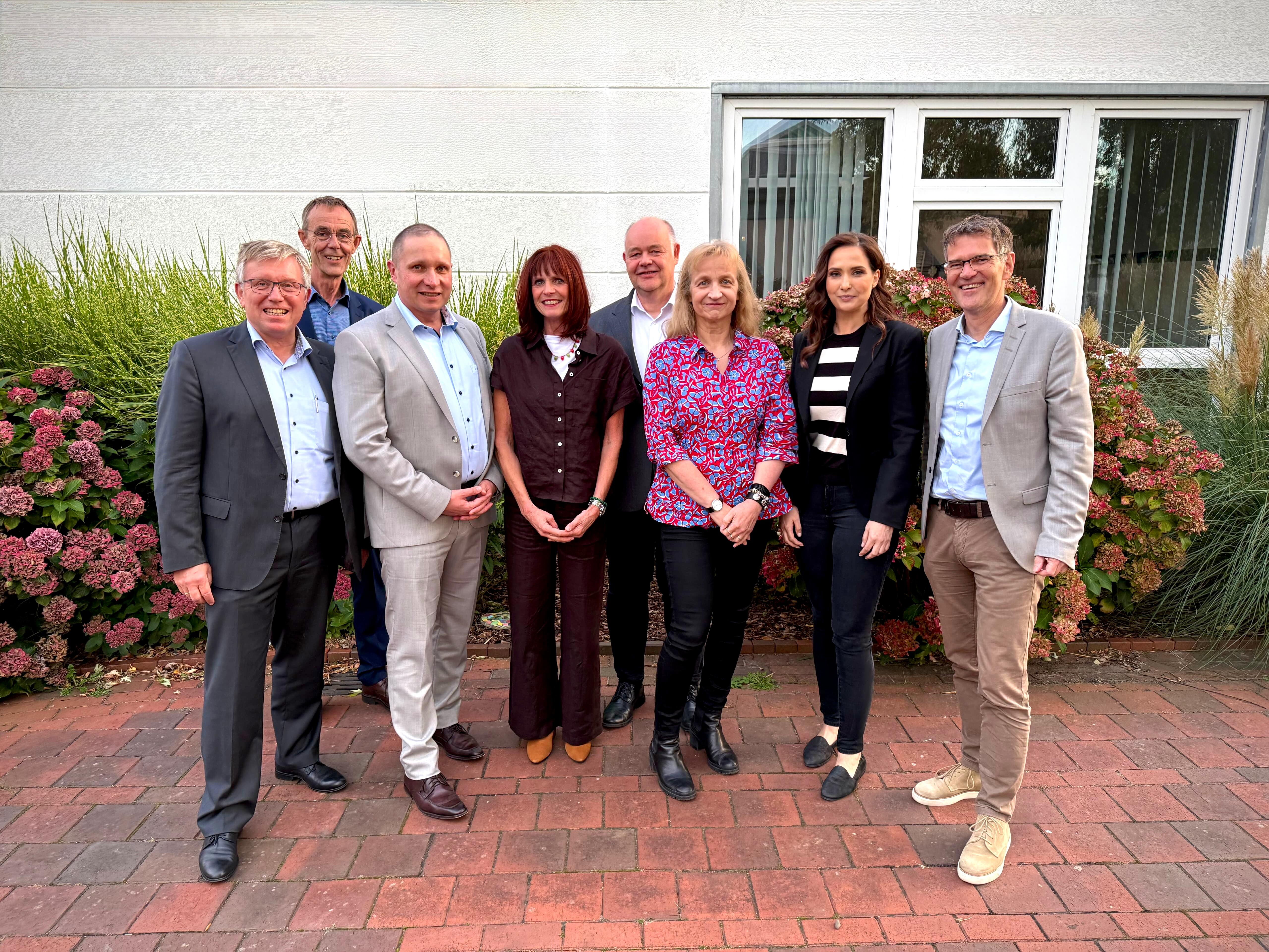 Personengruppe vor einem Haus mit Hortensien