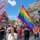 Junge Frau mit bunter Flagge und Parität-Logo auf dem Bremer Marktplatz , im Hintergrund viele Menschen