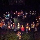 Menschen mit Lichtern stehen im Dunkel und bilden ein Lichterherz - Aufnahme aus der Vogelperspektive