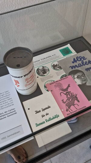 Ausstellungsstücke: Alte Spendendose, alte Schriften und Flyer