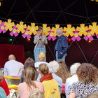 2 Personen auf einer Bühne mit bunten Papierblumen und Ballons vor Publikum