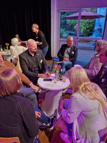 Verschiedene Männer und Frauen sitzen um einen Tisch und sprechen